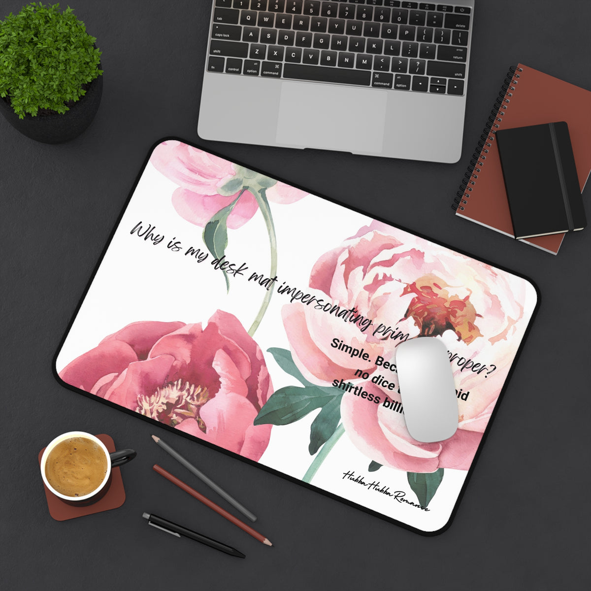 The desk mat is displayed with a laptop nearby and a mouse on it, with assorted office items lying on the desk as well.
