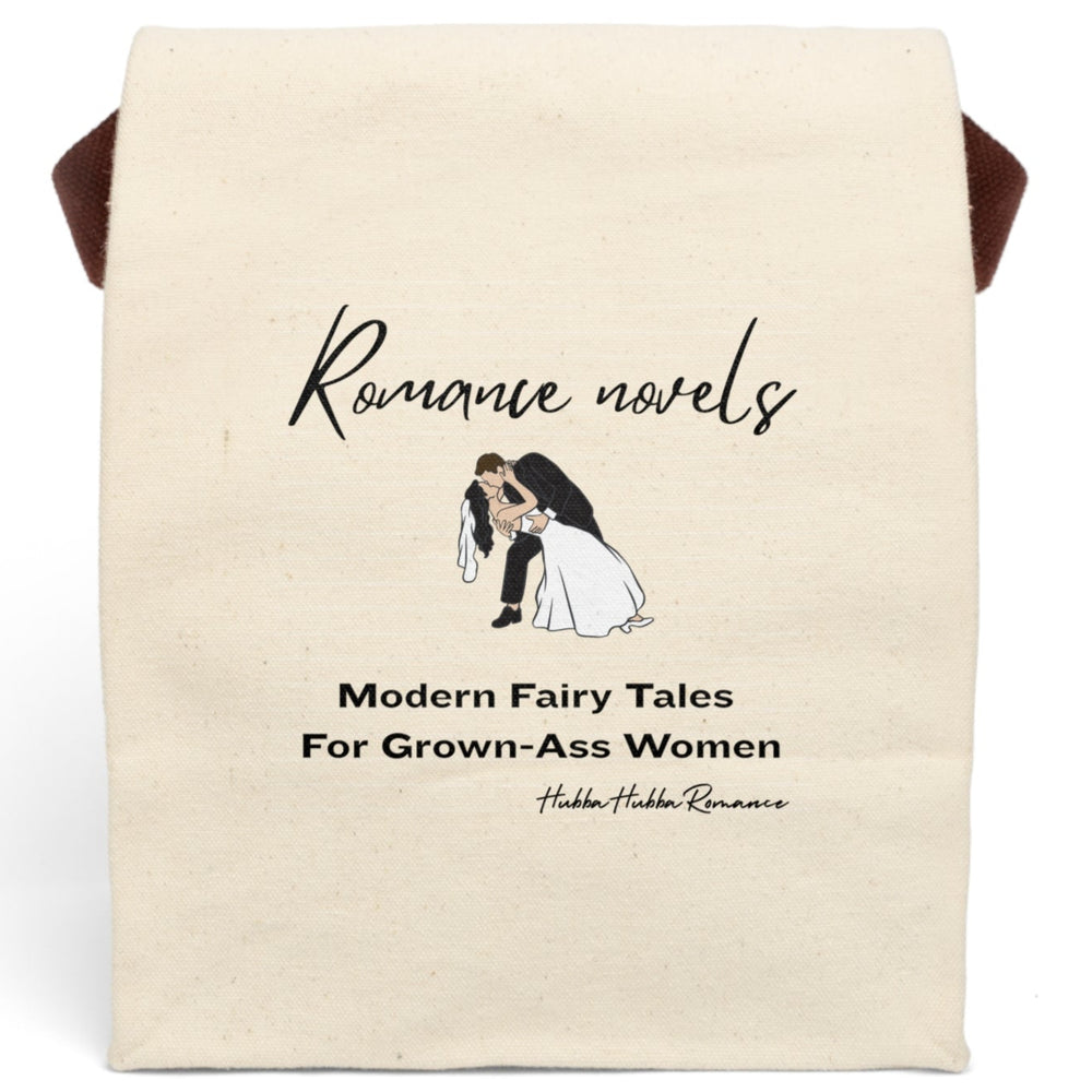This canvas lunch bag features a plain canvas background with black text. At the top, the words “Romance novels” are written in an elegant script font. Below is an illustration of a bride and groom in a classic dip-kiss pose—the groom in a black suit, the bride in a flowing white gown and veil. Under the image, large bold text reads: “Modern Fairy Tales For Grown-Ass Women.” The design is romantic with a cheeky edge. The bag has a roll-top closure and canvas strap.