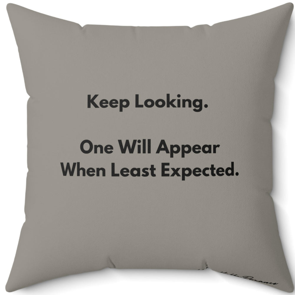 This is the back of the pillow. It has the same muted "grayish olive greenish" background color as the front of the pillow with text that reads  “Keep Looking. One Will Appear When Least Expected.”