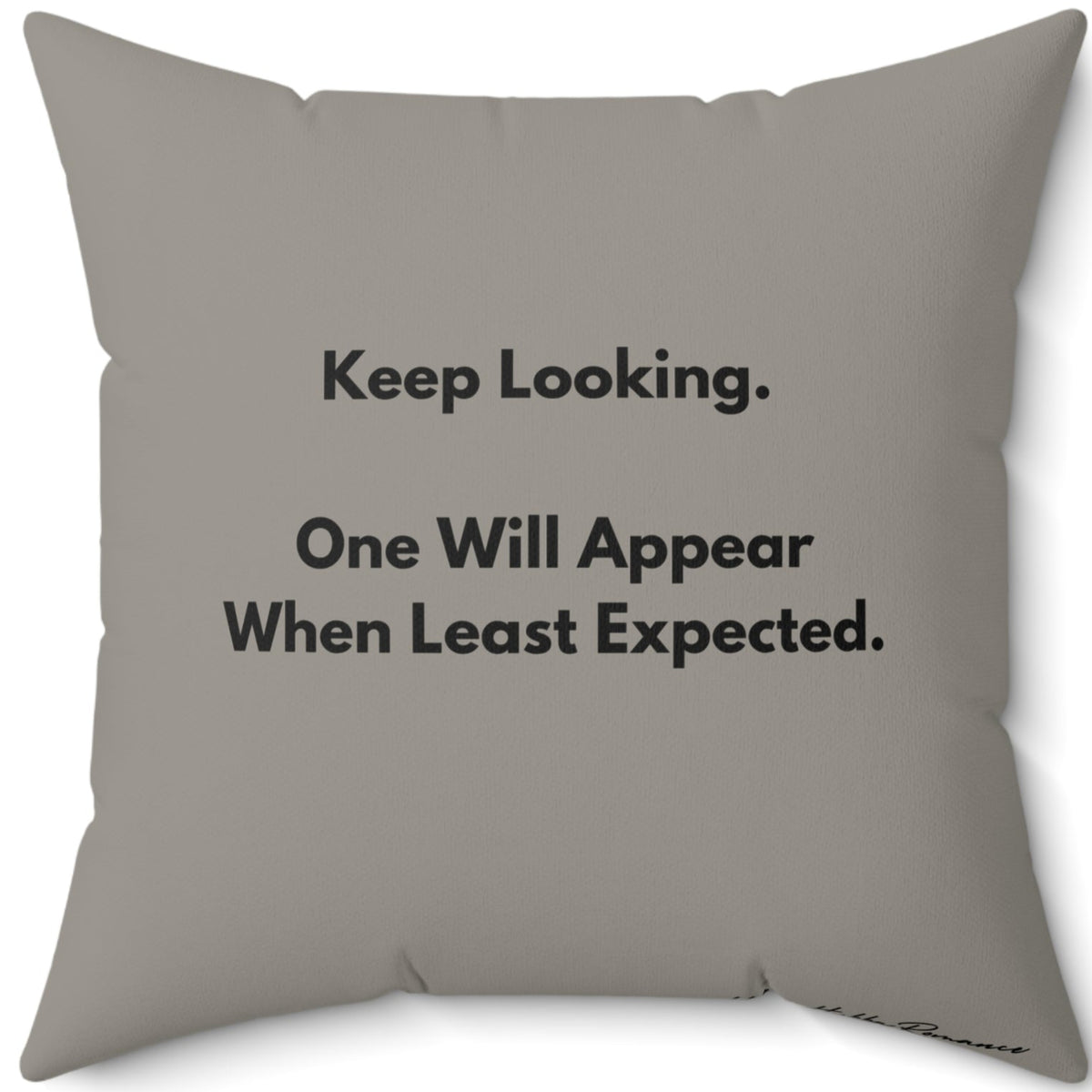 This is the back of the pillow. It has the same muted "grayish olive greenish" background color as the front of the pillow with text that reads  “Keep Looking. One Will Appear When Least Expected.”