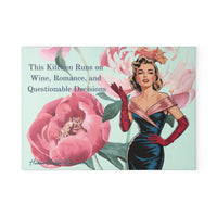 Glass cutting board with a watercolor floral background featuring pink peonies. A retro glamour woman in a strapless black and pink dress with long red gloves stands at the side. The text reads: “This kitchen runs on wine, romance, and questionable decisions.” Made of tempered glass with non-slip rubber feet for countertop use. This is the smaller size.