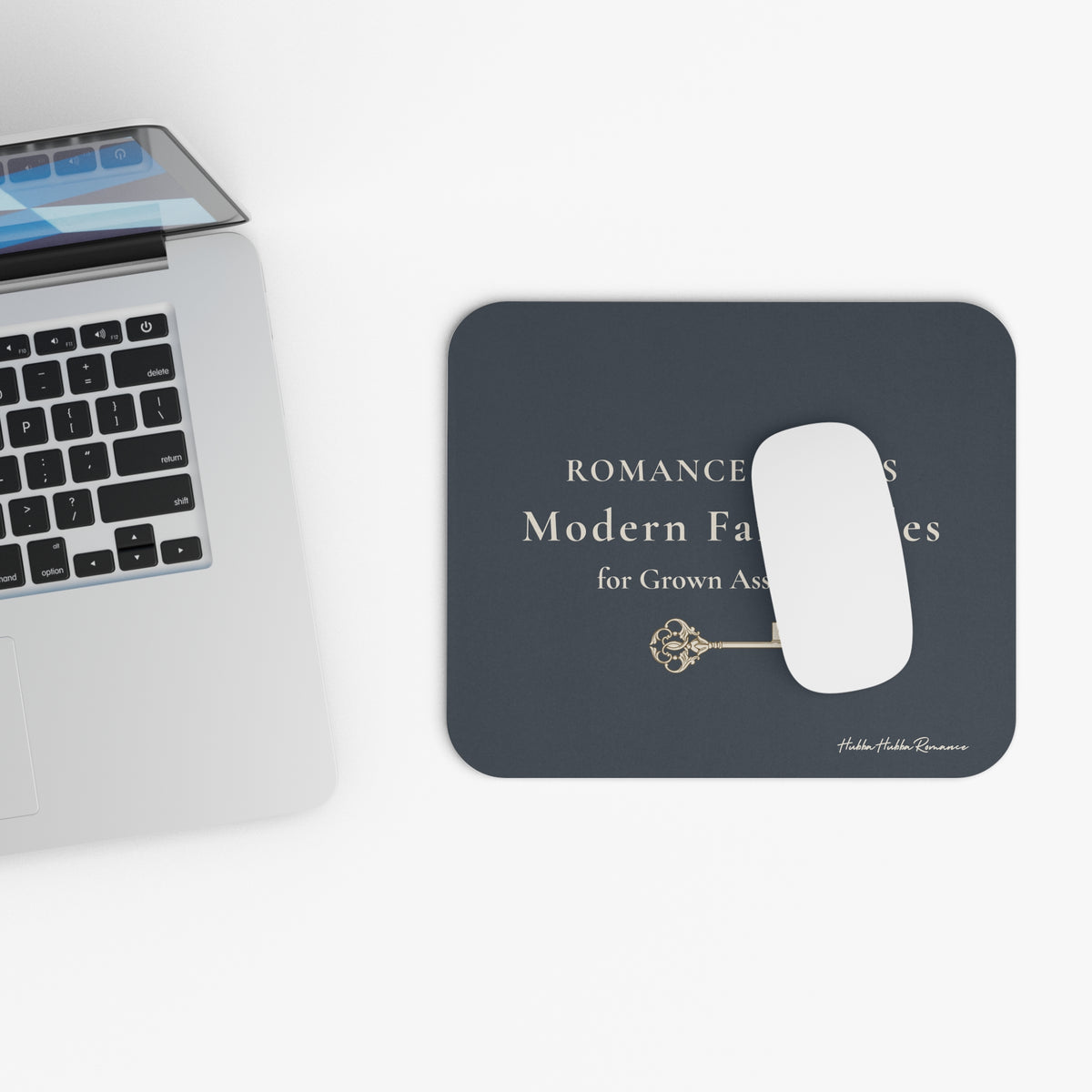 Black mouse pad with a white mouse on a desk next to a laptop