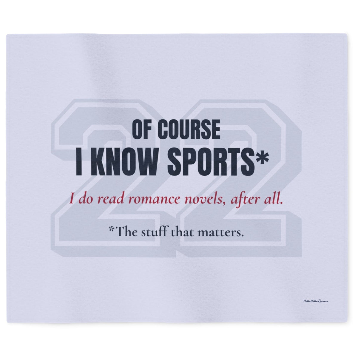 A light blueish gray sweatshirt blanket featuring a printed graphic with the text 'OF COURSE I KNOW SPORTS*' in dark navy, 'I do read romance novels, after all.' in red, and '*The stuff that matters in dark blue font. A large and very faded 22 in block numbers sits behind the text.