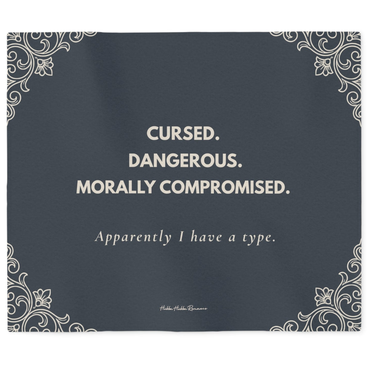 Slate gray sweatshirt blanket featuring the quote "Cursed. Dangerous. Morally Compromised. Apparently I have a type." with elegant gothic corner flourishes. The font and the corner flourishes are in a cream color.