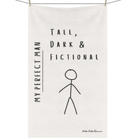 An off-white kitchen towel featuring an image of a male stick figure along with the words: My Perfect Man. Tall, Dark, and Fictional hangs on a clothesline secured by clothespins.
