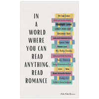 The image features a cotton kitchen towel with a colorful stack of romance books on the right, accompanied by a column of vertical text to the left that reads: 'In a World Where You Can Read Anything, Read Romance.'

