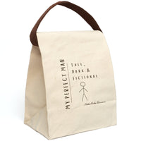 This canvas lunch bag features a minimalist, hand-drawn design on a plain canvas background. On the left, vertical text reads “MY PERFECT MAN.” To the right, in a casual handwritten font, it says: “Tall, Dark & Fictional.” Below the text is a simple brown stick figure drawing of a man. The design is playful and tongue-in-cheek. The bag includes a durable canvas body, roll-top enclosure, and strap—ideal for everyday use by book lovers and romance readers. The strap is displayed upright.