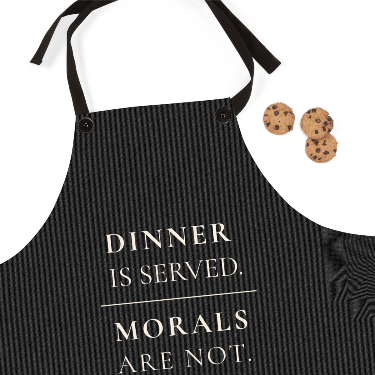A black apron with cream colored text reading 'DINNER IS SERVED. MORALS ARE NOT.