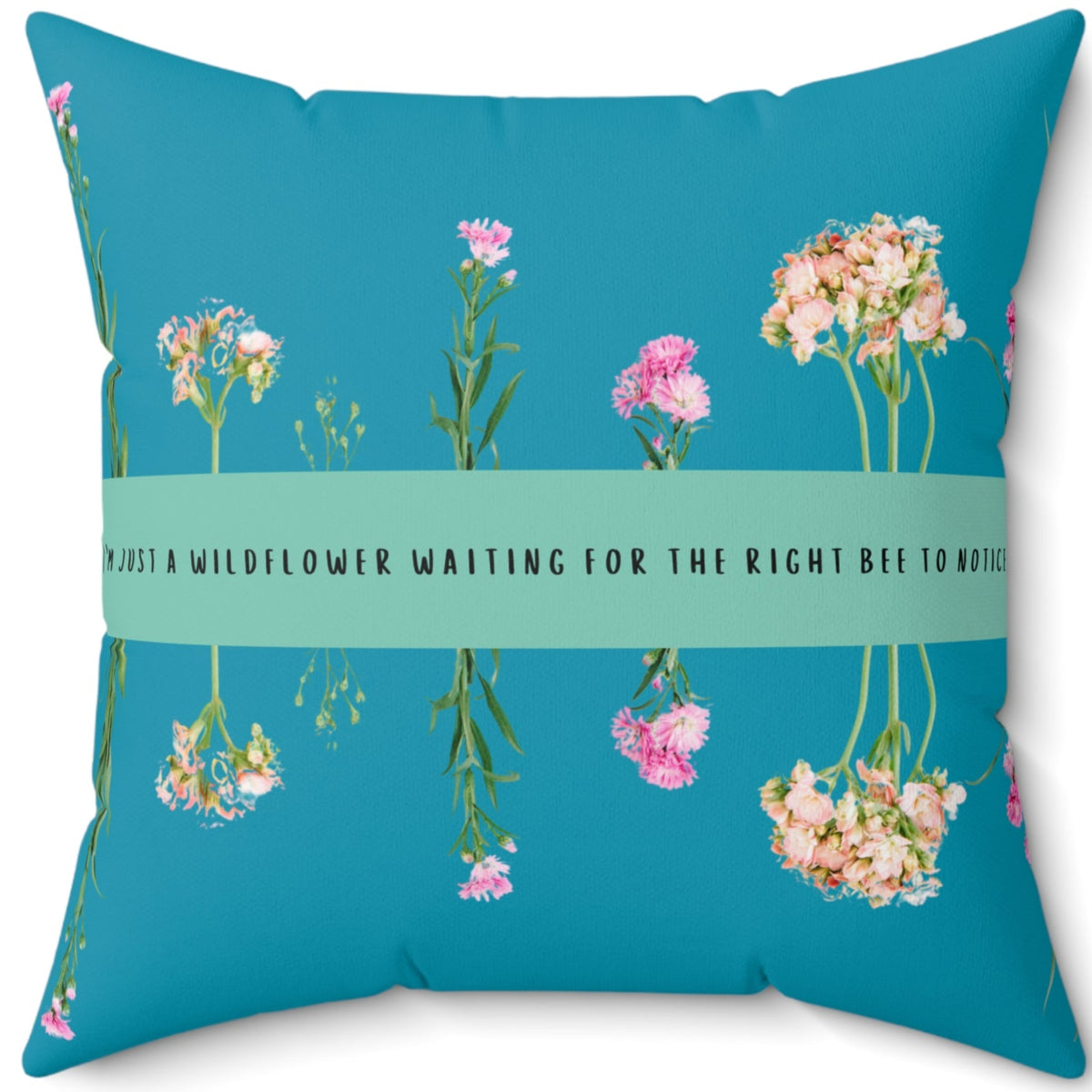 A 20-inch pillow that features an arrangement of delicate wildflowers, some upright and others hanging upside down, against a vibrant teal background. A horizontal light green banner stretches across the center, displaying the phrase "I'm just a wildflower waiting for the right bee to notice." in black text. The design is whimsical and romantic, symbolizing patience, individuality, and the hope of finding the perfect match.