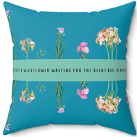 A 20-inch pillow that features an arrangement of delicate wildflowers, some upright and others hanging upside down, against a vibrant teal background. A horizontal light green banner stretches across the center, displaying the phrase "I'm just a wildflower waiting for the right bee to notice." in black text. The design is whimsical and romantic, symbolizing patience, individuality, and the hope of finding the perfect match.