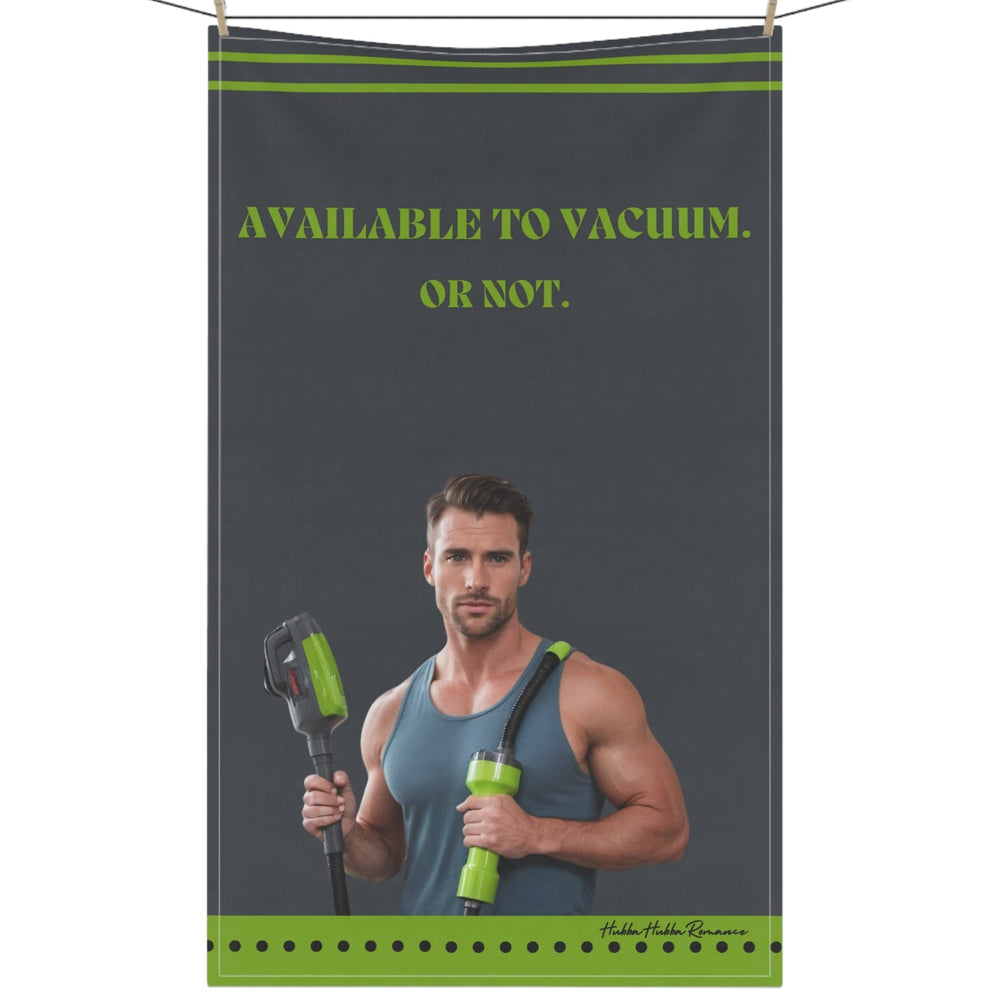 The image shows a kitchen towel with a grey background and a vintage-style illustration of a smiling man in a muscle shirt using a vacuum cleaner. He wears jeans and has a confident, playful expression. Lime green bold text reads: "Available To Vacuum. Or Not." The design combines retro charm with cheeky humor, making it a fun and sassy accessory for romance readers who appreciate a little double entendre with their cleaning vibes. The kitchen towel is displayed on a clothesline.