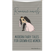 The kitchen towel is displayed on a clothesline and features a vintage-inspired design with a retro-style bride and groom in wedding attire. The groom, dressed in a classic suit, dips the bride, who wears a flowing wedding dress. Above them, vintage cursive black text reads: "Romance Novels," and below them, in block script, "Fairy Tales for Grown-Up Women." The background is taupe-ish khaki, pin-striped, giving it a nostalgic, classic romance feel. The design is perfect for book lovers of HEA endings.