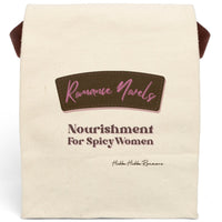 This lunch bag features a plain canvas background with two prominent text sections. At the top, a stylized brown label with pink stitching contains the words “Romance Novels” in a cursive pink font. Below the label, bold pink and brown text reads: “Nourishment For Spicy Women.” The design resembles a vintage food label with a modern, sassy twist. The bag is made of durable canvas with a roll-top closure and a carrying strap, perfect for everyday use.