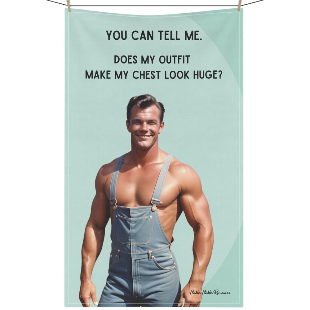 The kitchen towel features a playful, vintage-style illustration of a smiling, muscular man wearing denim overalls without a shirt. He stands confidently with his hands on his hips, highlighting his muscular chest and arms. Bold black text humorously reads: "You Can Tell Me. Does My Outfit Make My Chest Look Huge?" The background is neutral, allowing the humorous image and text to stand out. Perfect for readers who appreciate playful humor in their kitchen accessories.The towel is displayed on a clothesline