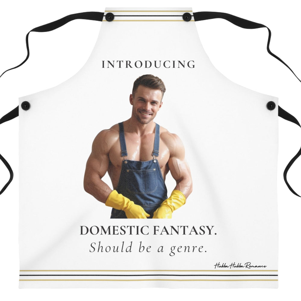 A white kitchen apron with black neck and waist ties, featuring a printed graphic of a shirtless muscular man in blue overalls and yellow gloves with the text 'INTRODUCING DOMESTIC FANTASY. Should be a genre.