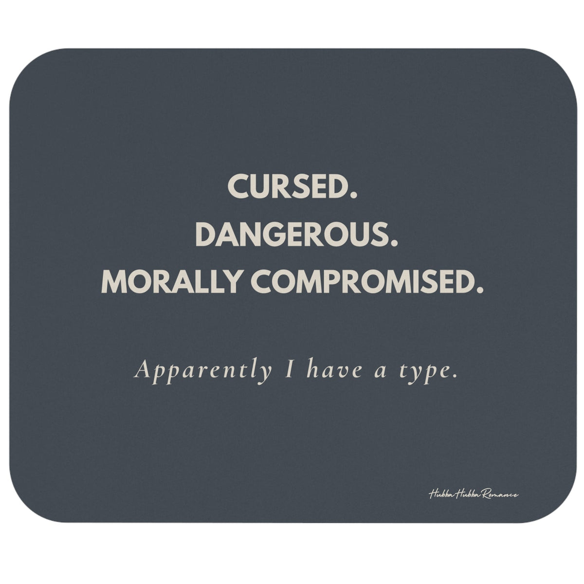 A rectangular dark slate-gray mouse pad with rounded corners, featuring the text 'CURSED. DANGEROUS. Morally Compromised. Apparently I have a type in cream letters.