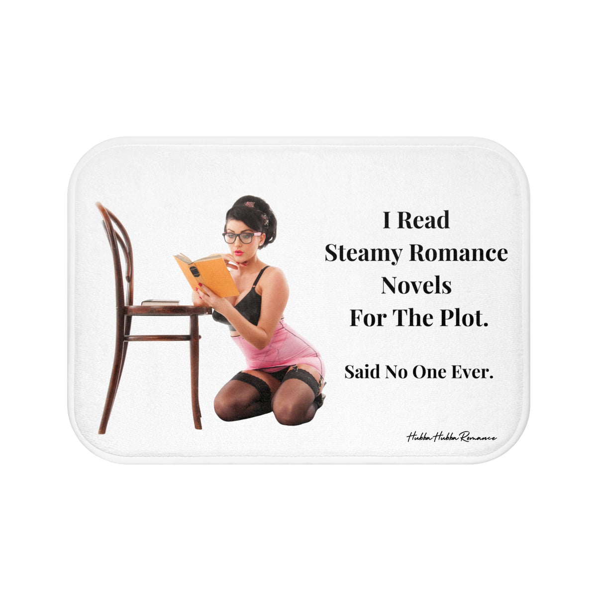 This bath mat showcases a vintage pin-up style image of a woman kneeling beside a wooden chair, engrossed in a book. She is dressed in a pink corset, black lingerie, stockings, and glasses, styled with retro hair and makeup. To the right, bold black text reads: “I Read Steamy Romance Novels For The Plot. Said No One Ever.” The background is solid white, featuring striking text and playful imagery. The mat is soft and absorbent. This is the smallerr size.