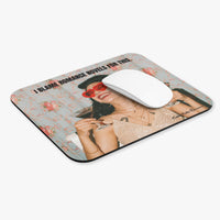 A rectangular mouse pad with rounded corners featuring a printed graphic of a woman in red sunglasses and a black hat on a floral light blue background, with the text 'I BLAME ROMANCE NOVELS FOR THIS.' A white computer mouse rests on top.