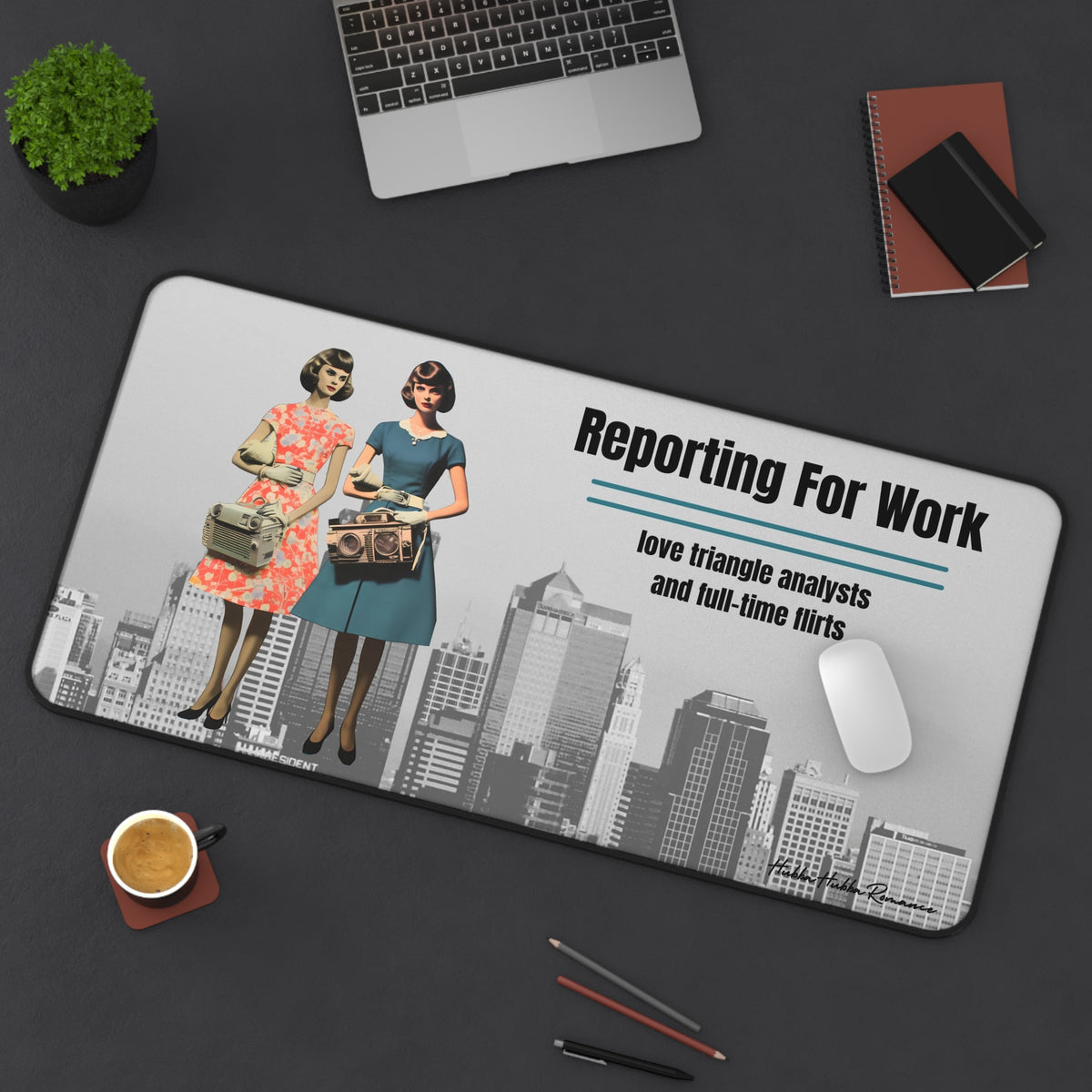 The desk mat is displayed with a laptop nearby and a mouse on it, with assorted office items lying on the desk as well.
