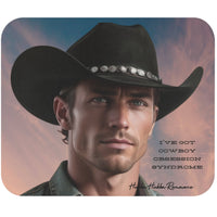A digital art portrait of a handsome cowboy in a black hat and denim shirt, staring intently into the distance with a sunset background. Black text in a bold western font reads, “I’ve Got Cowboy Obsession Syndrome.” Ideal for romance fans and western decor lovers.