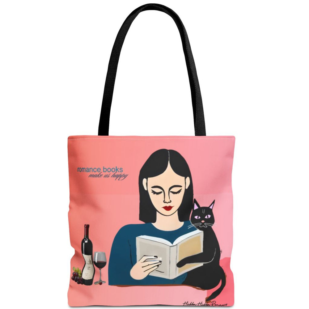 Tote bag with pink-to-coral gradient background, illustrated woman with long black hair reading, black cat resting on book, and text: “Romance Books Make Us Happy.” Wine bottle, glass, and grapes beside her.