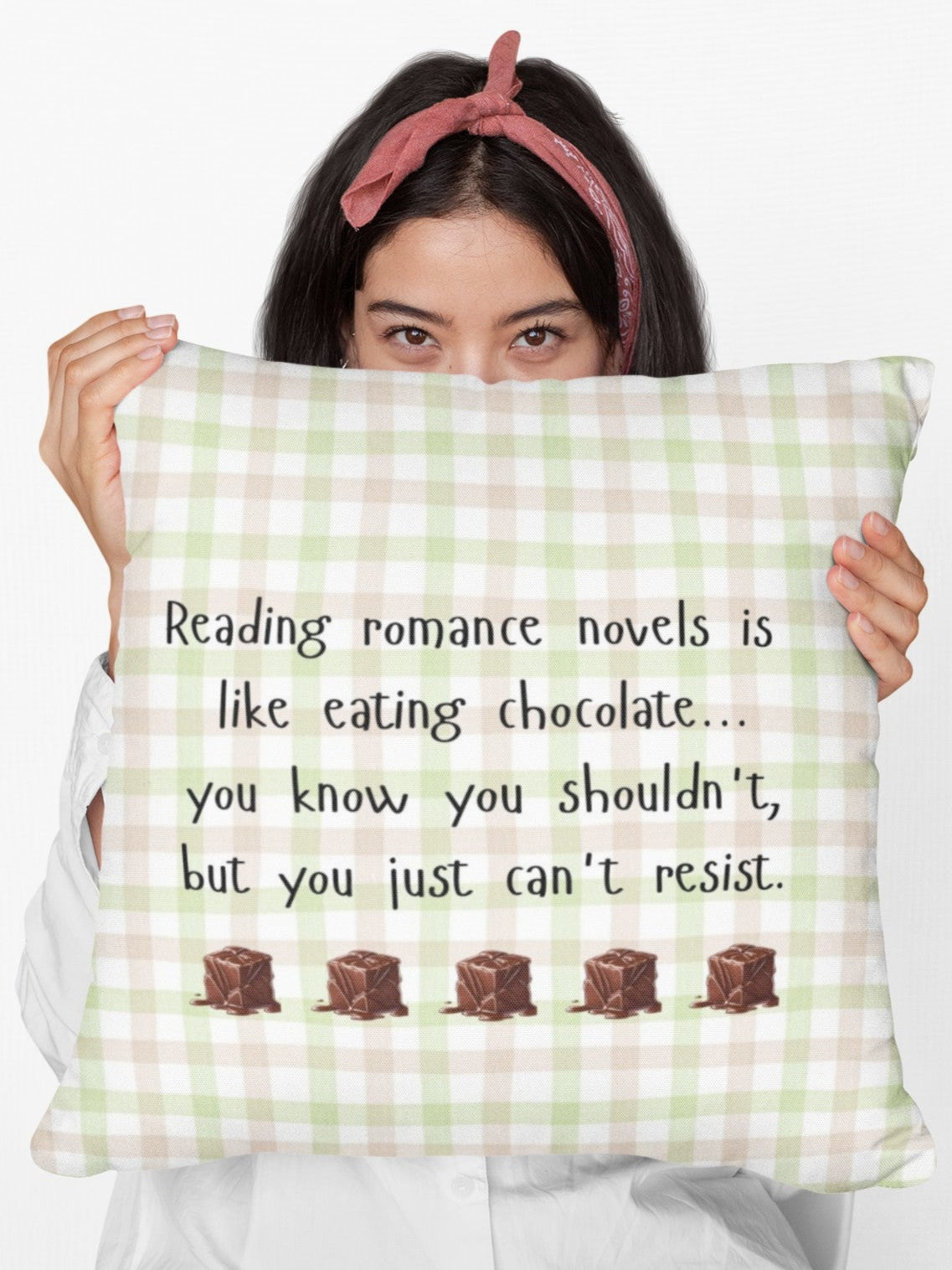 A digital image featuring a woman in a white shirt holding a pillow in light green and pink gingham background with black handwritten-style text that reads: "Reading romance novels is like eating chocolate… you know you shouldn’t, but you just can’t resist." Below the text, five illustrated chocolate pieces with a glossy, melting effect are lined up in a row. The overall design has a cozy, playful feel, combining a love for romance books with the indulgence of chocolate.