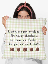 A digital image featuring a woman in a white shirt holding a pillow in light green and pink gingham background with black handwritten-style text that reads: "Reading romance novels is like eating chocolate… you know you shouldn’t, but you just can’t resist." Below the text, five illustrated chocolate pieces with a glossy, melting effect are lined up in a row. The overall design has a cozy, playful feel, combining a love for romance books with the indulgence of chocolate.