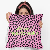 A woman holds a 20-inch  square pillow with a bold pink and black leopard print background. Across the center, the words “fictional heartbreaks” are written in stylish cursive and block lettering in neon lime- green. The vibrant design is playful and edgy, appealing to romance readers who love dramatic love stories. 

