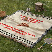 The blanket has colorful cotton fringed edges. The blanket is being displayed as a picnic blanket in a park setting with a tree stump, picnic basket, plate of muffins, and a tennis racquet and a soccer ball lying around.

