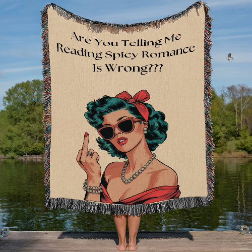 A woven cotton fringed blanket with an illustration of a woman wearing sunglasses and a red scarf, with text 'Are You Telling Me Reading Spicy Romance Is Wrong???', displayed by a person standing on a wooden pier.
