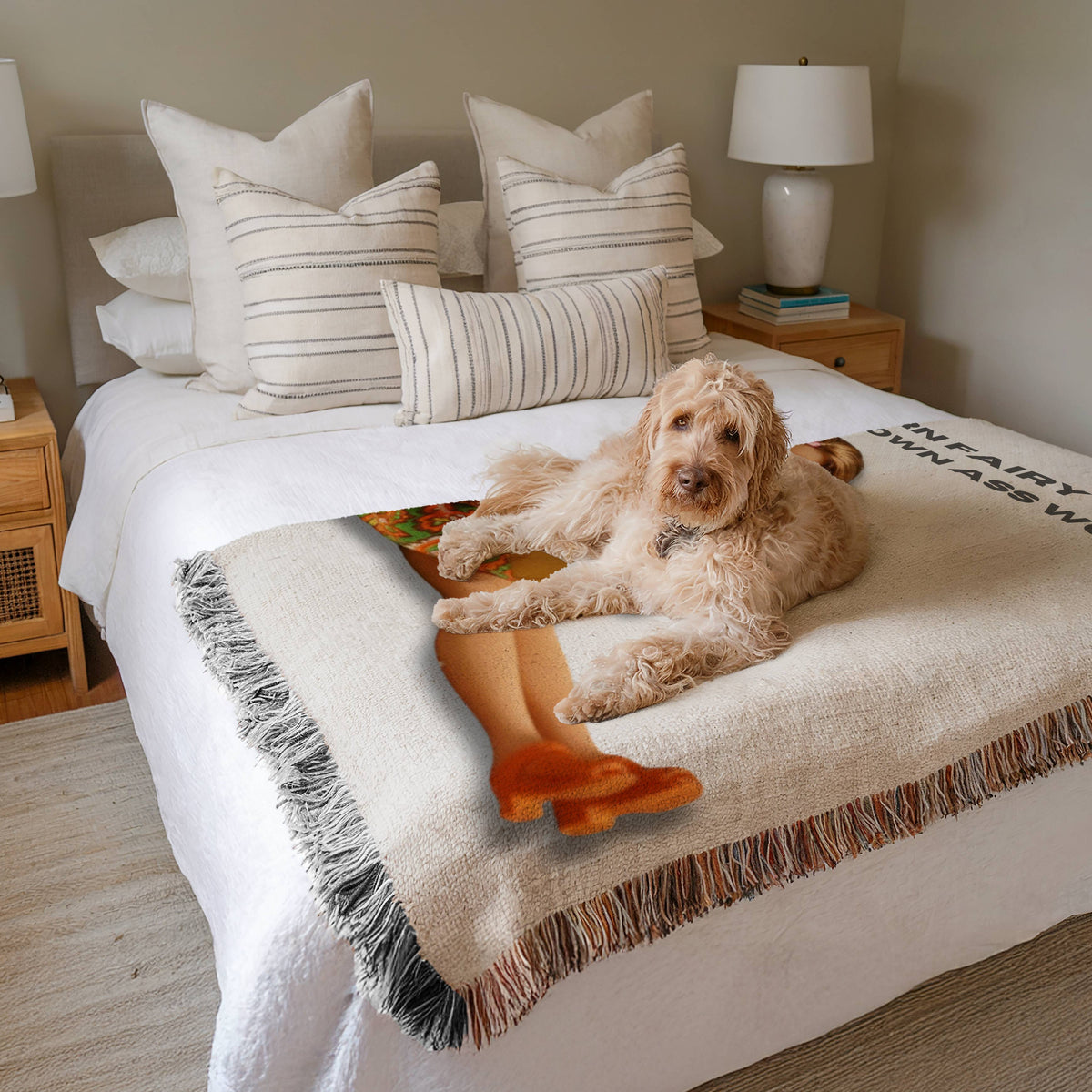 Cozy woven blanket draped across a bed with a dog resting on top. The blanket features a retro brunette reader illustration and the phrase “Modern Fairy Tales for Grown Ass Women.” Bookish home decor and gift for romance readers.