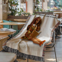 Woven fringe blanket displayed over a chair in a cozy café setting. Features a vintage-inspired reading heroine with pink-streaked hair and the phrase “Modern Fairy Tales for Grown Ass Women.” Decorative throw blanket for romance readers and book lovers.