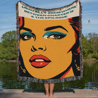 Colorful woven cotton fringe blanket featuring vintage-inspired pop art woman artwork displayed on a lakeside dock, designed for readers who love romance novels. the phrase "Mentally Somewhere Between Chapter 12 & The Epilogue," designed for romance readers, book lovers, and bookish home décor enthusiasts.
