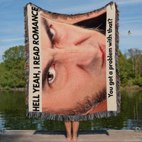 Funny woven blanket featuring an angry man's face and the phrase Hell Yeah I Read Romance displayed by a person holding it outdoors on a dock.