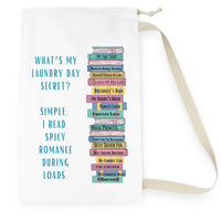  This is an image of an off white laundry bag lying flat on its side. It has a drawstring enclosure at the top and a large canvas carrying strap on the side. The bag has an image of a large stack of romance books with various spicy titles. Next to the stack is text that says: What's My Laundry Secret? Simple. I read Spicy Romance During Loads. This is the smaller bag.