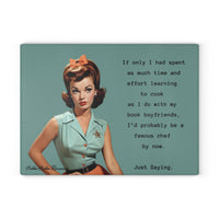 Glass cutting board with a vintage-style image of a woman in a mint green blouse and coral skirt with an orange bow in her hair. The text reads: “If only I had spent as much time and effort on food prep as I do with my book boyfriends, I’d probably be a famous chef by now. Just saying.” Board is rectangular with a textured, tempered glass surface and rubber feet for stability. This is the smaller version.
