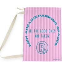 This laundry bag features a pink background with vertical pastel-pink stripes. Centered, bold, teal text reads: "All the good ones are taken." Above the text, in a large curved arc, it says: “Men are like parking spaces!” Below the quote is a parking symbol: a capital letter “P” inside a circle with a car icon in the corner. The bag includes a drawstring closure and a canvas carrying strap. The tone is playful, retro, and full of tongue-in-cheek charm. It is the large version.