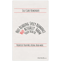 An off white cotton kitchen towel that is text based with the following message displayed in black text: "Self-Care Reminder” in a banner format at the top of the towel. Under it is “Not Reading Spicy Romance May Actually Harm Your Health” in 3 levels of nested arched text. “Prioritize Your Well-being. Read More." Is also in a banner format under the arched text. The saying is meant to be sarcastically ironic. 