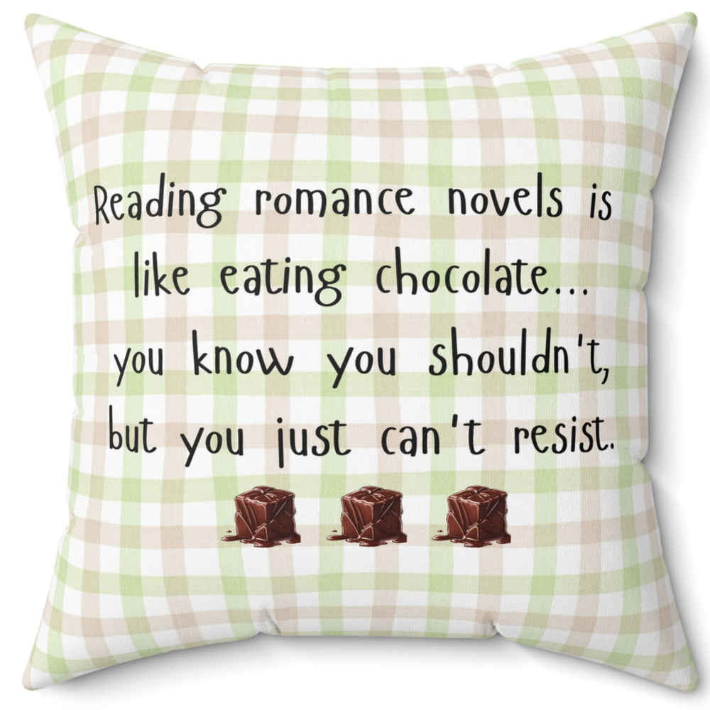 Square pillow with a beige , pink and green plaid background. Black playful text says: “Reading romance novels is like eating chocolate… you know you shouldn’t, but you just can’t resist.” Three illustrated chocolate pieces sit along the bottom. A cheeky decorative pillow for romance readers.