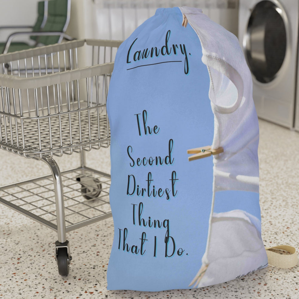 This laundry bag features two white tank tops pinned to a clothesline against a bright blue sky. To the left side of the t-shirts is a playful message in elegant black text: “Laundry. The second dirtiest thing that I do.” The visual combines clean imagery with cheeky humor, making it a fun and functional bag for readers who love steamy romance and tidy piles. The bag has a drawstring closure and a large canvas strap for carrying. This is the large version. It is displayed in front of a cart for size context