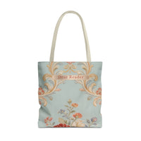 A canvas tote bag with cream-colored shoulder straps, featuring a light blue-green background decorated with a vintage-style damask pattern in gold, orange, and red, and a small label that reads 'Dear Reader'.