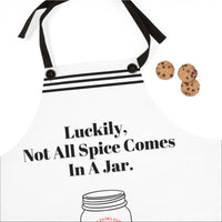 A close up of the white apron with black straps and a humorous design. The apron features the phrase, "Luckily, not all spice comes in a jar" .