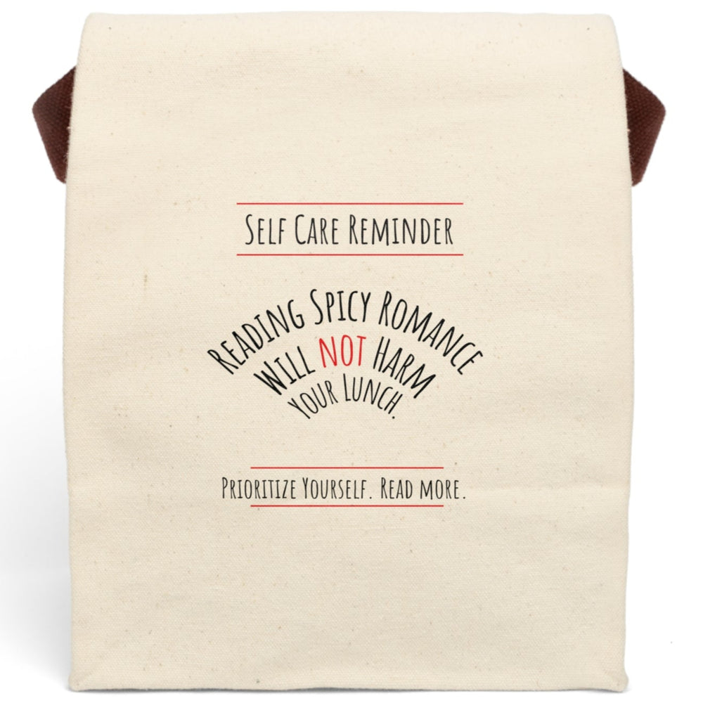 This canvas lunch bag design features black and red text on a white background. At the top, bold lettering reads: “Self-Care Reminder,” underscored with a red line. The main message is displayed in a curved arch and reads, “Reading Spicy Romance Will Not Harm Your Lunch,” with the word “Not” highlighted in red. At the bottom, text reads: “Prioritize Yourself. Read More,” also framed with red lines. The bag has a roll-top closure and a sturdy canvas carrying strap.