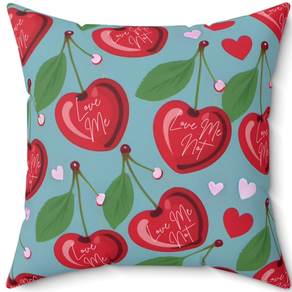 A 20-inch pillow features a playful pattern of heart-shaped cherries with green leaves and stems against a light blue background. Scattered among the cherries are small red and pink hearts. Each cherry is adorned with elegant white cursive text that alternates between "Love Me" and "Love Me Not," evoking the classic game of romantic uncertainty. The whimsical, romantic design combines a sweet aesthetic with a touch of flirtatious fun.