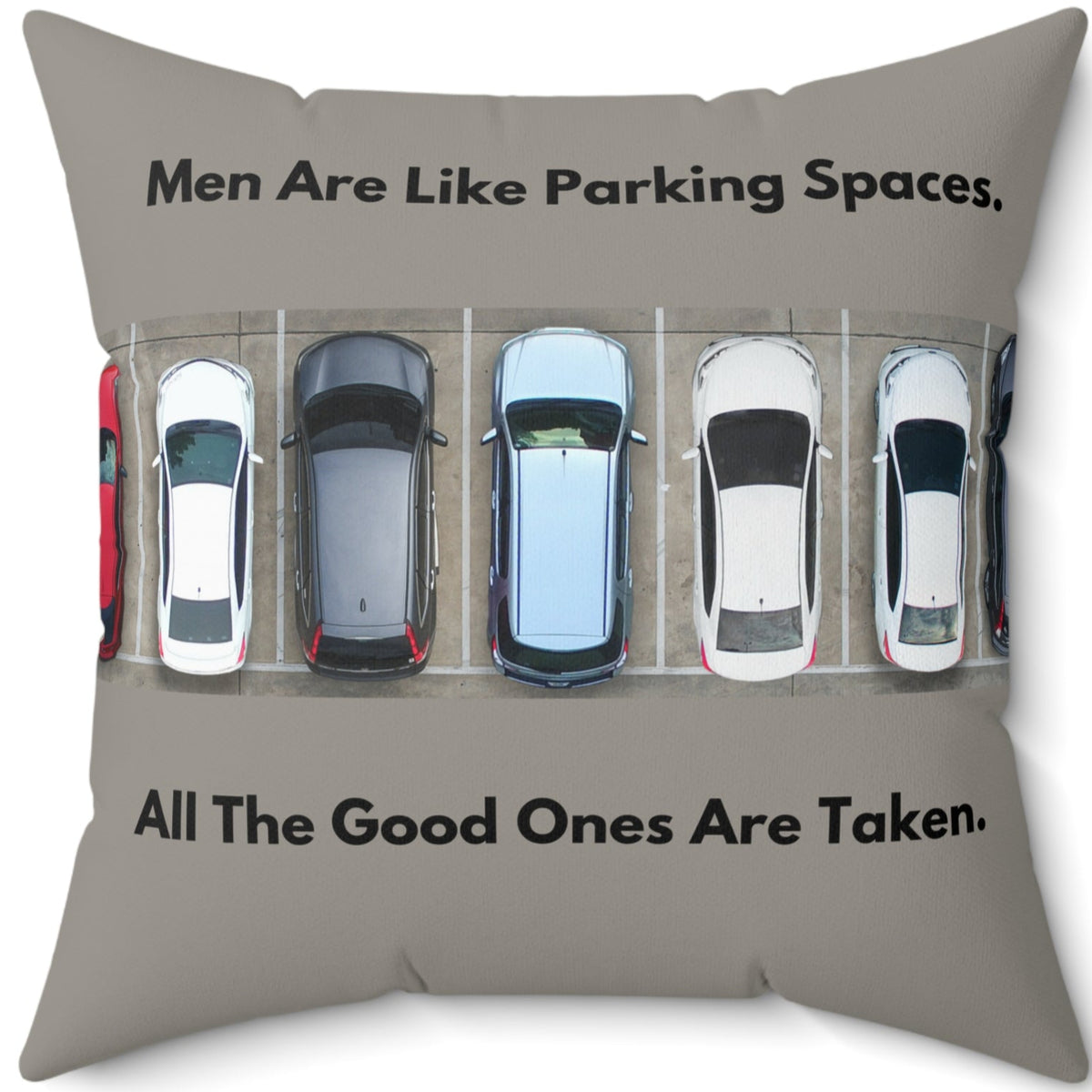 A 20-inch pillow features an overhead view of a row of parked cars in a parking lot. Above the image, bold black text reads: "Men Are Like Parking Spaces." Below the image, matching text continues: "All The Good Ones Are Taken." The background is a muted grayish-green, allowing the text and image to stand out. The design is playful and sarcastic, making a humorous comparison between dating and the struggle to find an available parking spot. 
