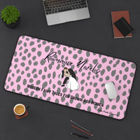 The desk mat is displayed with a laptop nearby and a mouse on it, with assorted office items lying on the desk as well.


