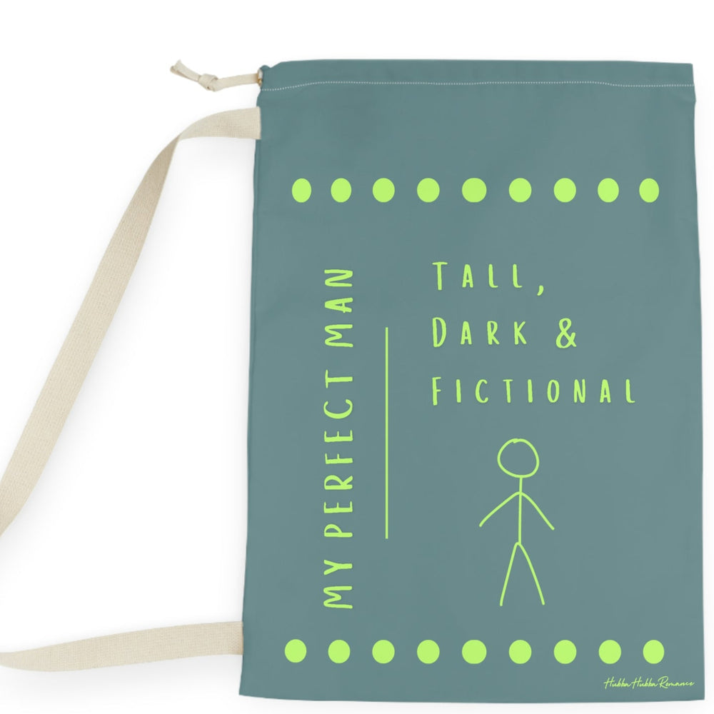 This laundry bag features a minimalist design on a muted greenish-gray background. A lime green stick figure stands next to bold lime green text that reads “Tall, Dark & Fictional,” with the words “My Perfect Man” printed vertically along the side. Rows of lime-green dots border the top and bottom of the bag. The bag includes a durable canvas carrying strap and a drawstring enclosure for secure, easy transport. This is the large version. 