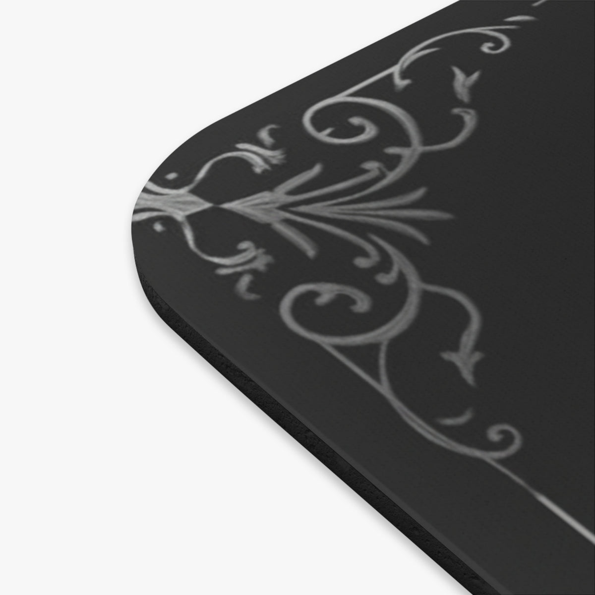 A close-up of the mousepad featuring a light gray ornate scroll pattern on a dark gray background.