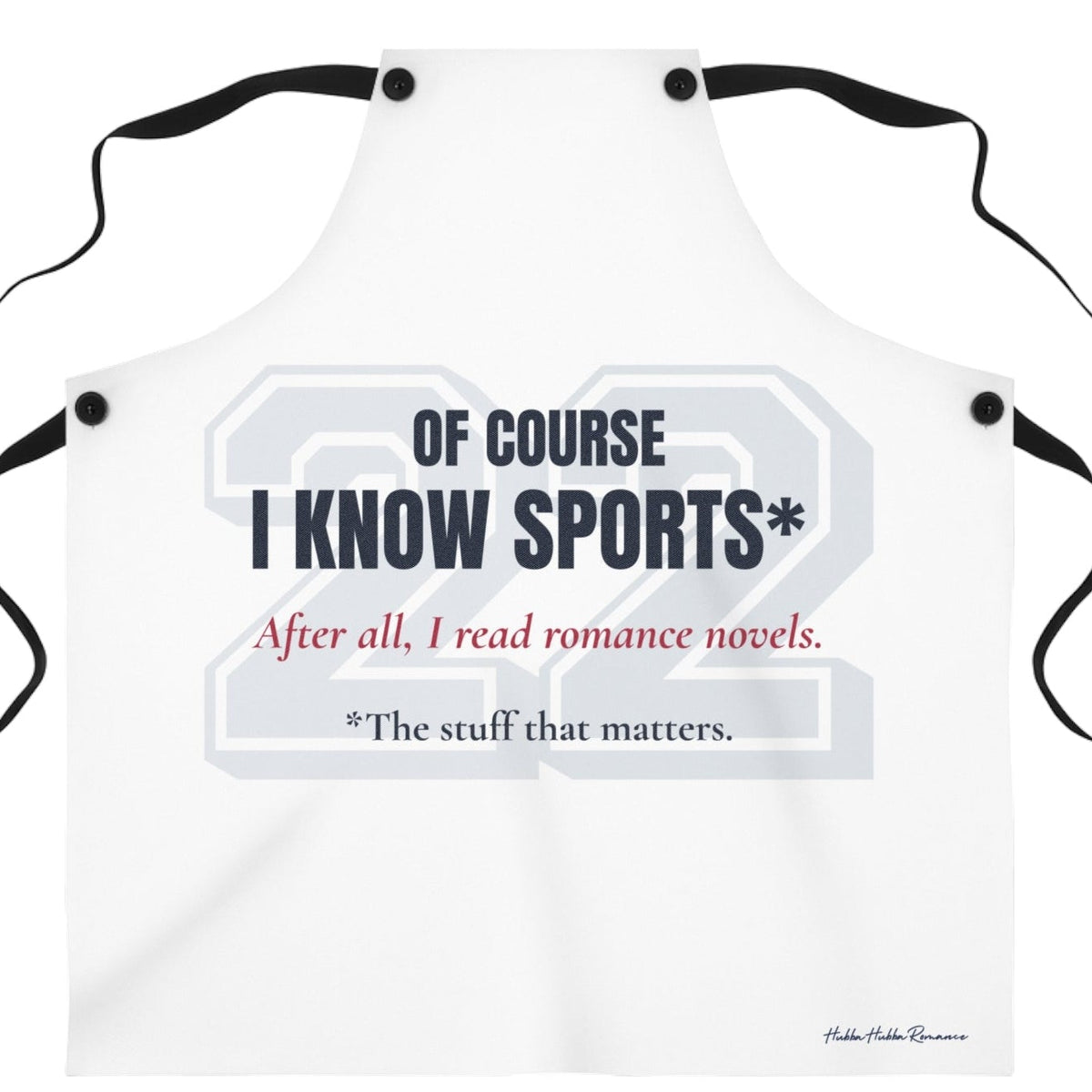 A white bib-style apron with black neck and waist ties, featuring a sports-themed graphic print that reads 'OF COURSE I KNOW SPORTS*' and 'After all, I read romance novels.' on a plain white background. There is an asterisk qualifying the sports knowledge to the stuff that matters.
