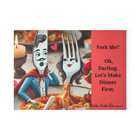 Glass cutting board featuring a playful cartoon illustration of a flirty fork and suave knife, personified with expressive faces. The fork is styled as a woman with long eyelashes and red lips, sitting in pasta with sauce. The knife, styled as a man with a mustache and cape, gazes at her with a heart floating between them. On a coral background, the text reads: “Fork Me? Oh, Darling, Let’s Make Dinner First.” Textured tempered glass with non-slip rubber feet. This is the smaller version.